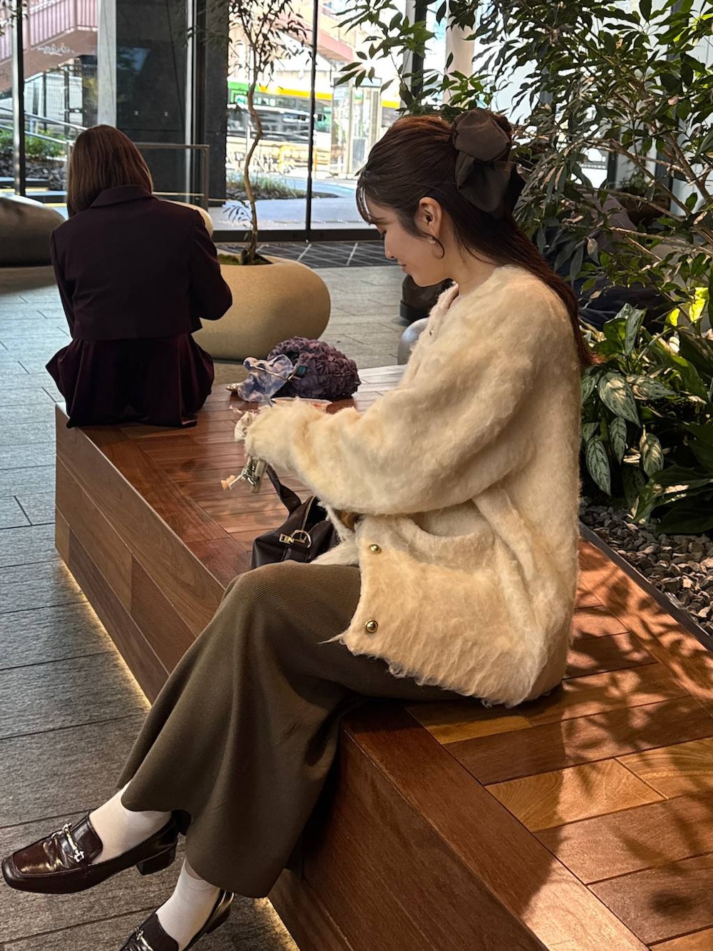 ブラウン系のボストンバッグ、ブラウン系のスカート、ホワイト系のカーディガン/ボレロを着用したレディースの冬コーディネートの3枚目の写真