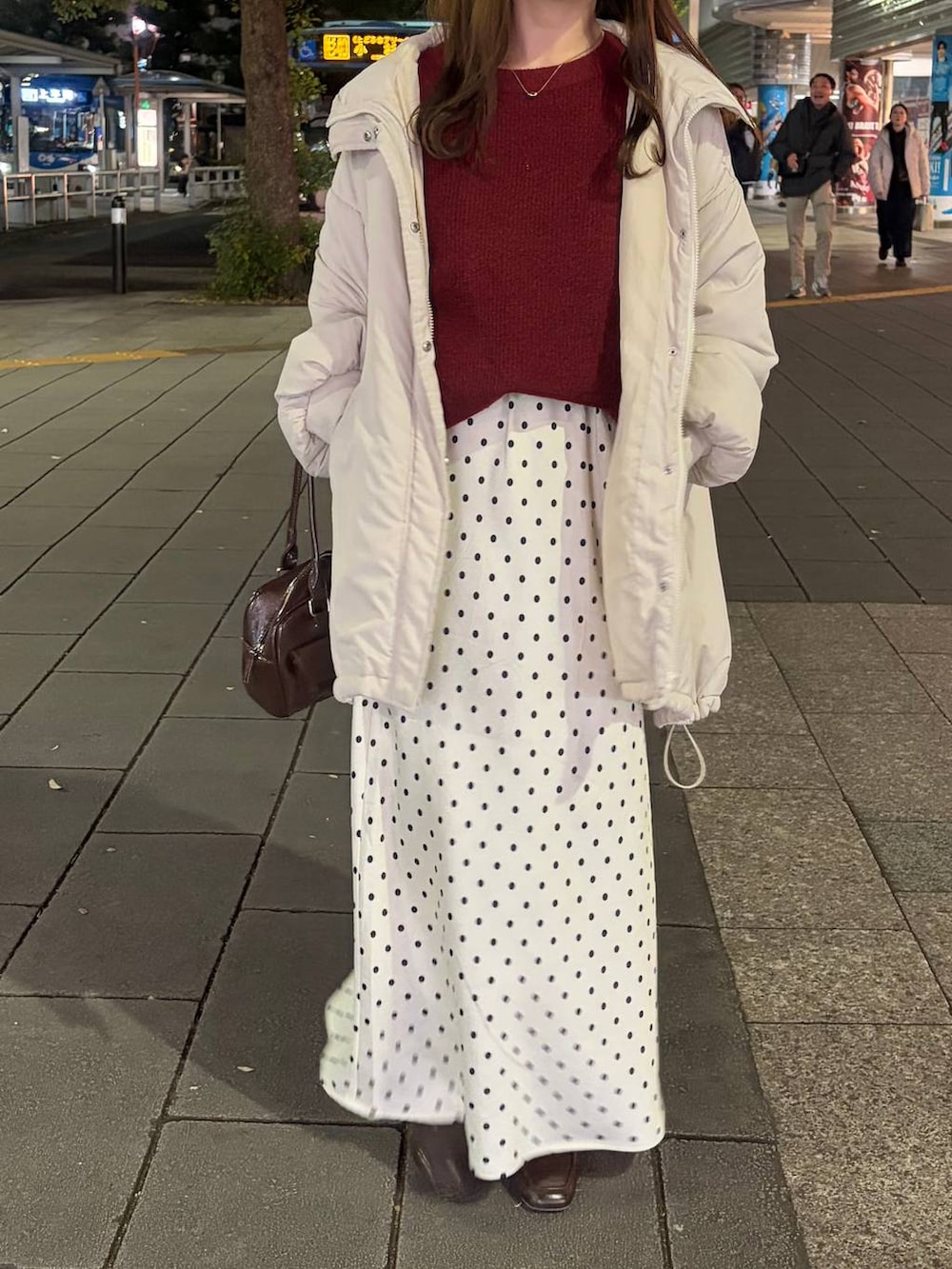 レッド系のニット/セーター、ホワイト系のブルゾン、ホワイト系のスカートを着用したレディースの冬コーディネートの2枚目の写真