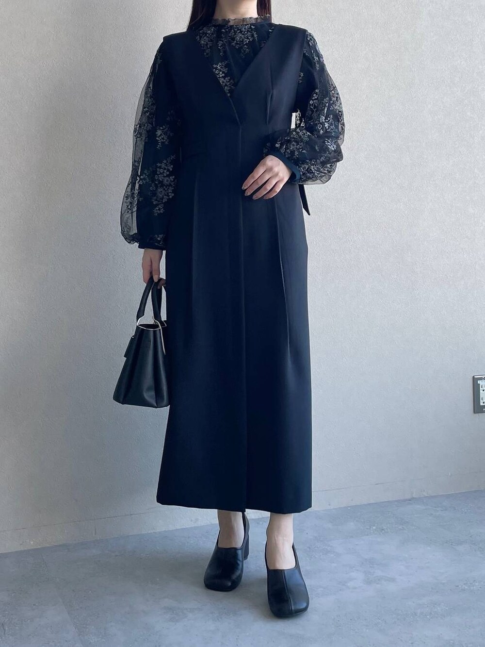 ブラック系のシャツ/ブラウス、ブラック系のショルダーバッグ、ブルー系のジャンパースカートを着用したレディースの冬コーディネートの4枚目の写真