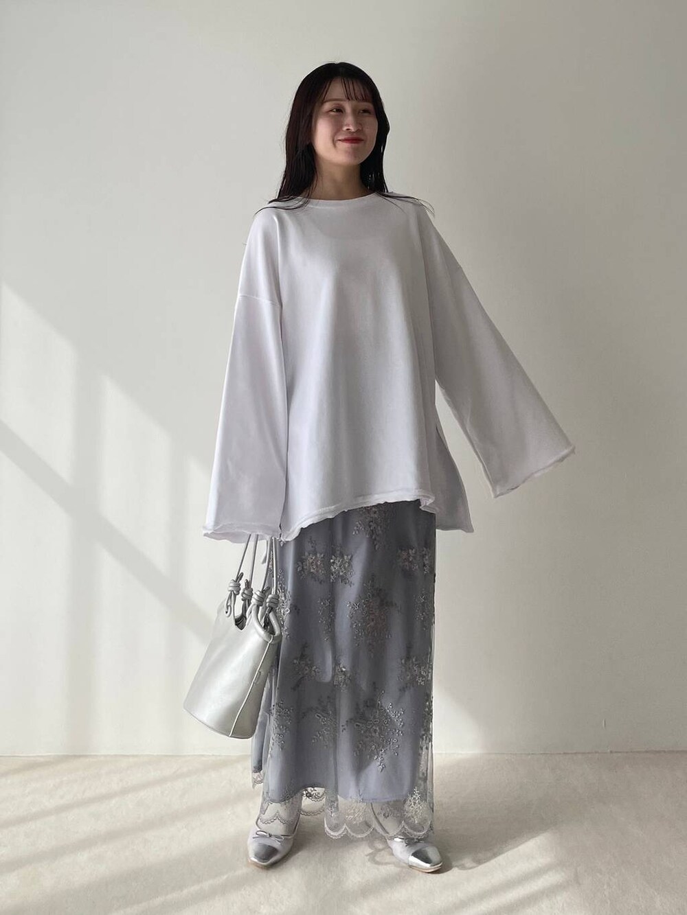 シルバー系のバレエシューズ、ホワイト系のスウェット、ブルー系のスカートを着用したレディースの春コーディネートの2枚目の写真