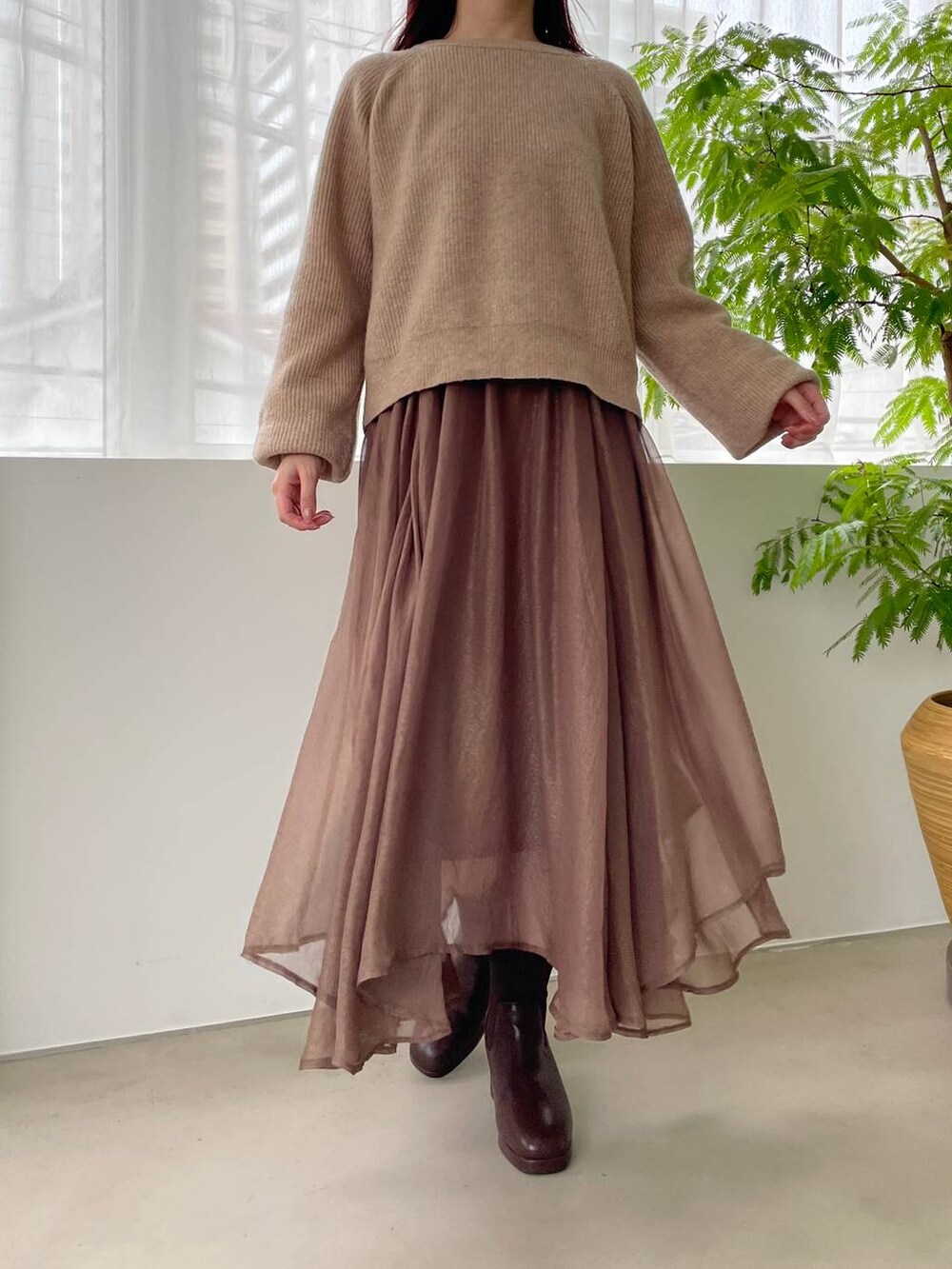 ホワイト系のショルダーバッグ、ブラウン系のブーツ、ベージュ系のニット/セーターを着用したレディースの冬コーディネートの3枚目の写真