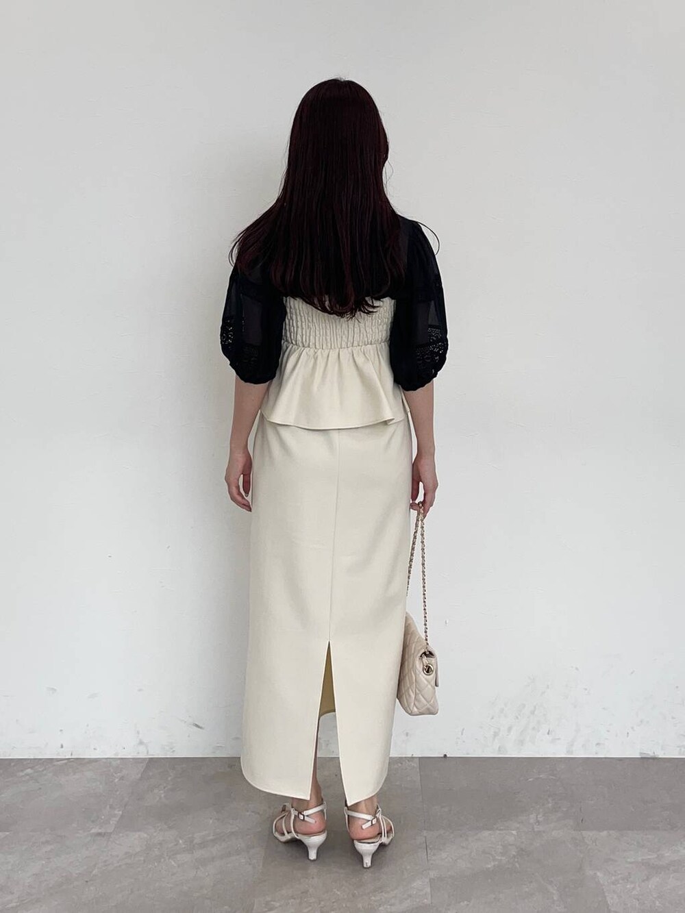 ホワイト系のスカート、ブラック系のシャツ/ブラウス、ホワイト系のショルダーバッグを着用したレディースの夏コーディネートの2枚目の写真