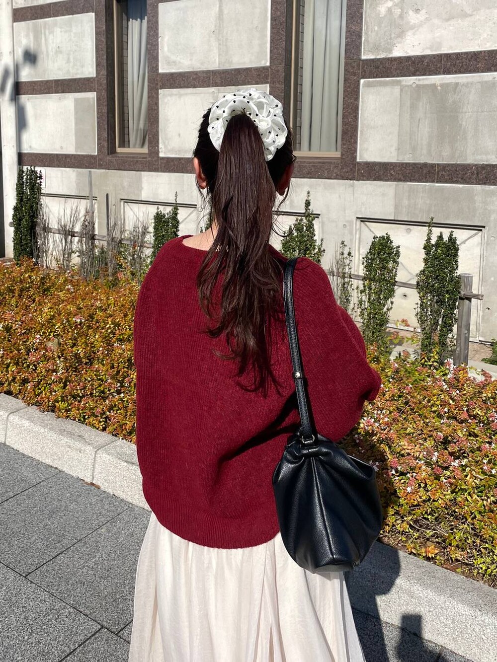 レッド系のニット/セーター、ホワイト系のブルゾン、ホワイト系のスカートを着用したレディースの秋コーディネートの8枚目の写真
