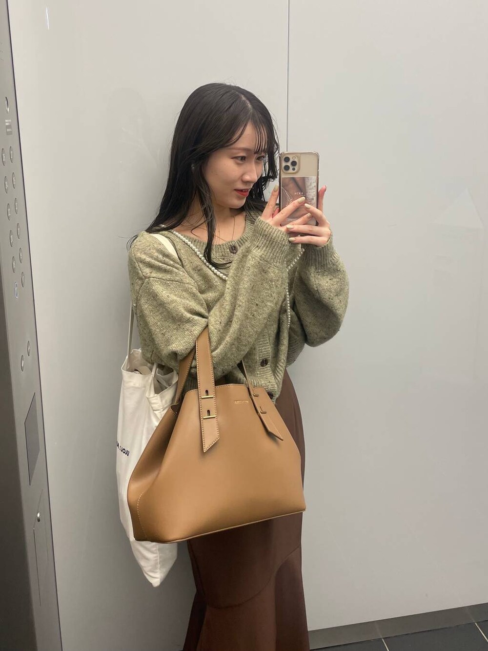 ブラウン系のスカート、グリーン系のカーディガン/ボレロ、ゴールド系のネックレスを着用したレディースの秋コーディネートの3枚目の写真