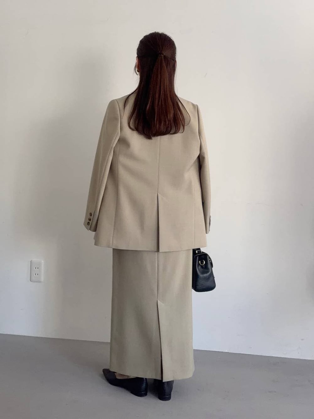 ブラック系のショルダーバッグ、ベージュ系のテーラードジャケット、ベージュ系のスカートを着用したレディースの冬コーディネートの2枚目の写真