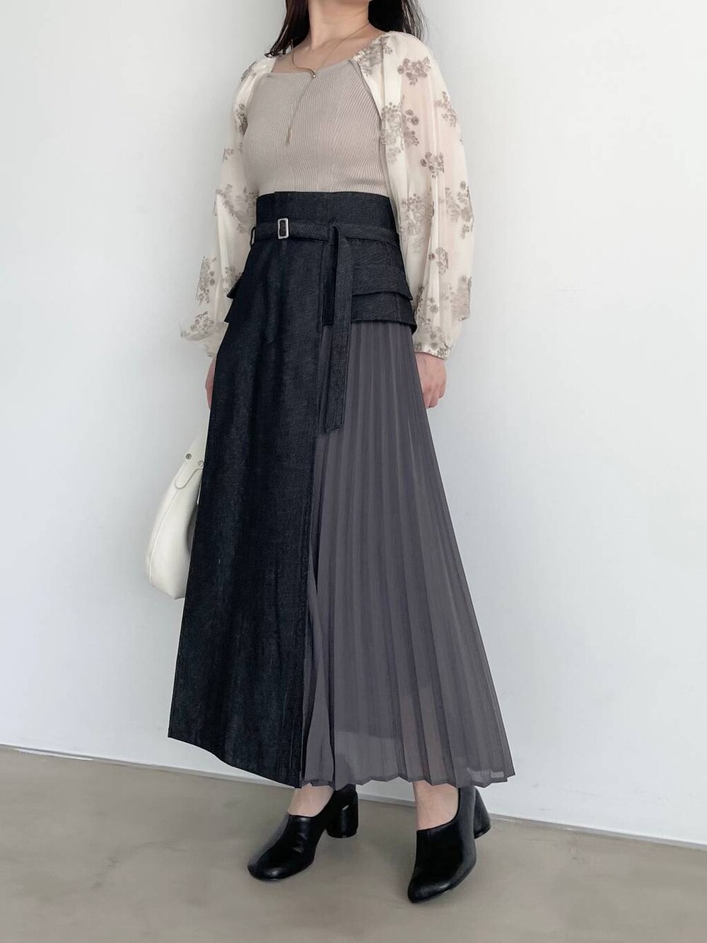 ブラック系のパンプス、ブラック系のスカート、ホワイト系のニット/セーターを着用したレディースの春コーディネートの4枚目の写真