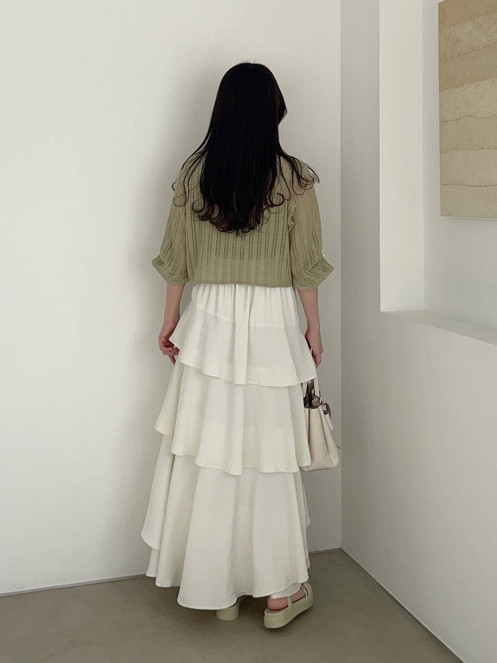 ホワイト系のスカート、ホワイト系のショルダーバッグ、グリーン系のカーディガン/ボレロを着用したレディースの春コーディネートの2枚目の写真