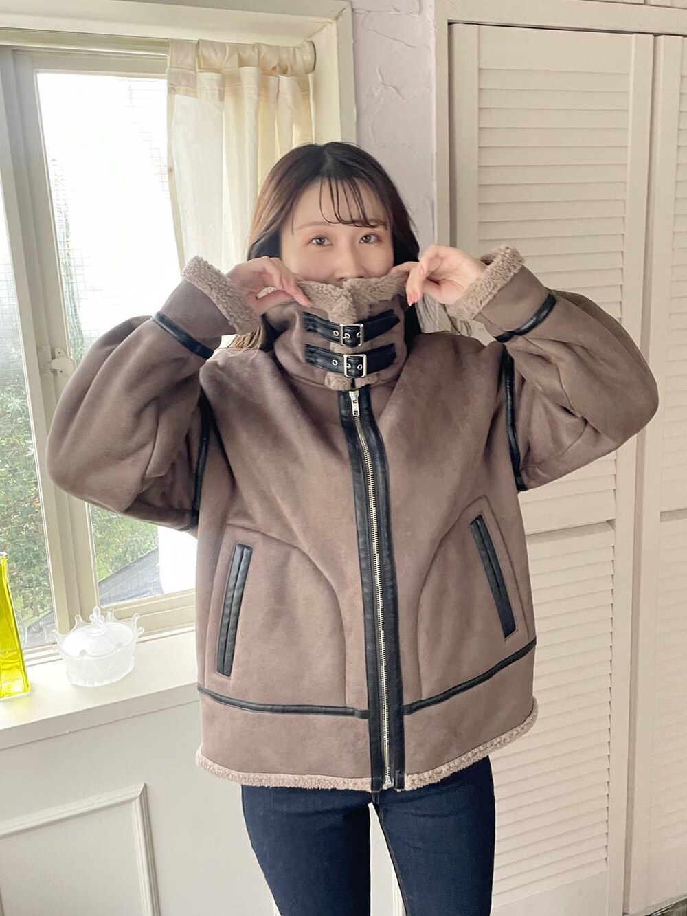 ブルー系のデニムパンツ、ブラウン系のハンドバッグ、ブラック系のブーツを着用したレディースの秋コーディネートの4枚目の写真