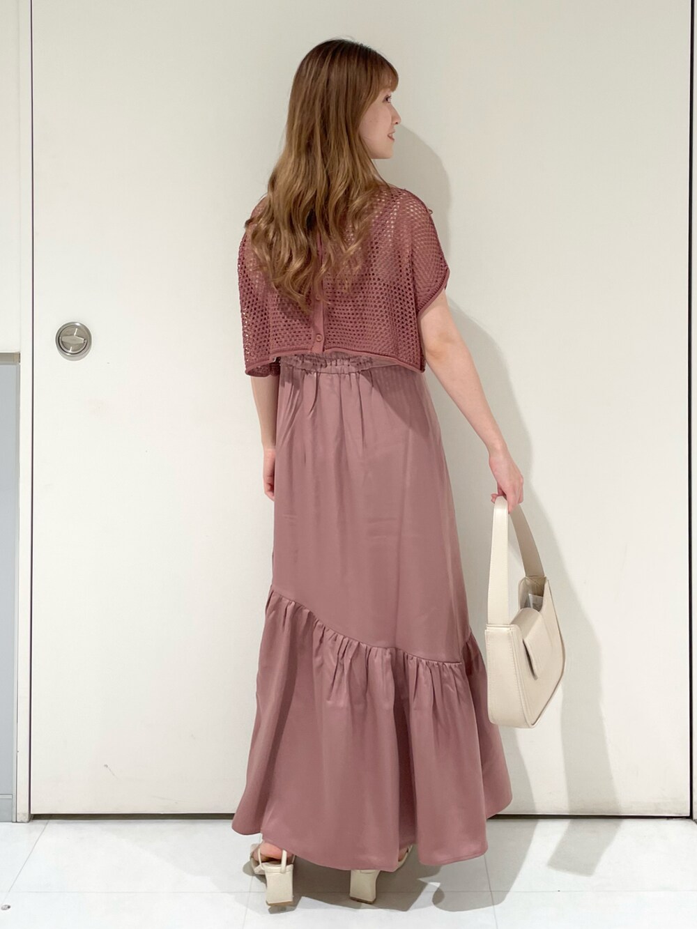 ピンク系のワンピース、ホワイト系のハンドバッグ、ホワイト系のサンダルを着用したレディースの夏コーディネートの2枚目の写真