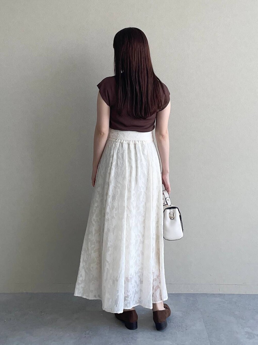 ホワイト系のショルダーバッグ、ブラウン系のニット/セーター、ホワイト系のスカートを着用したレディースの夏コーディネートの2枚目の写真