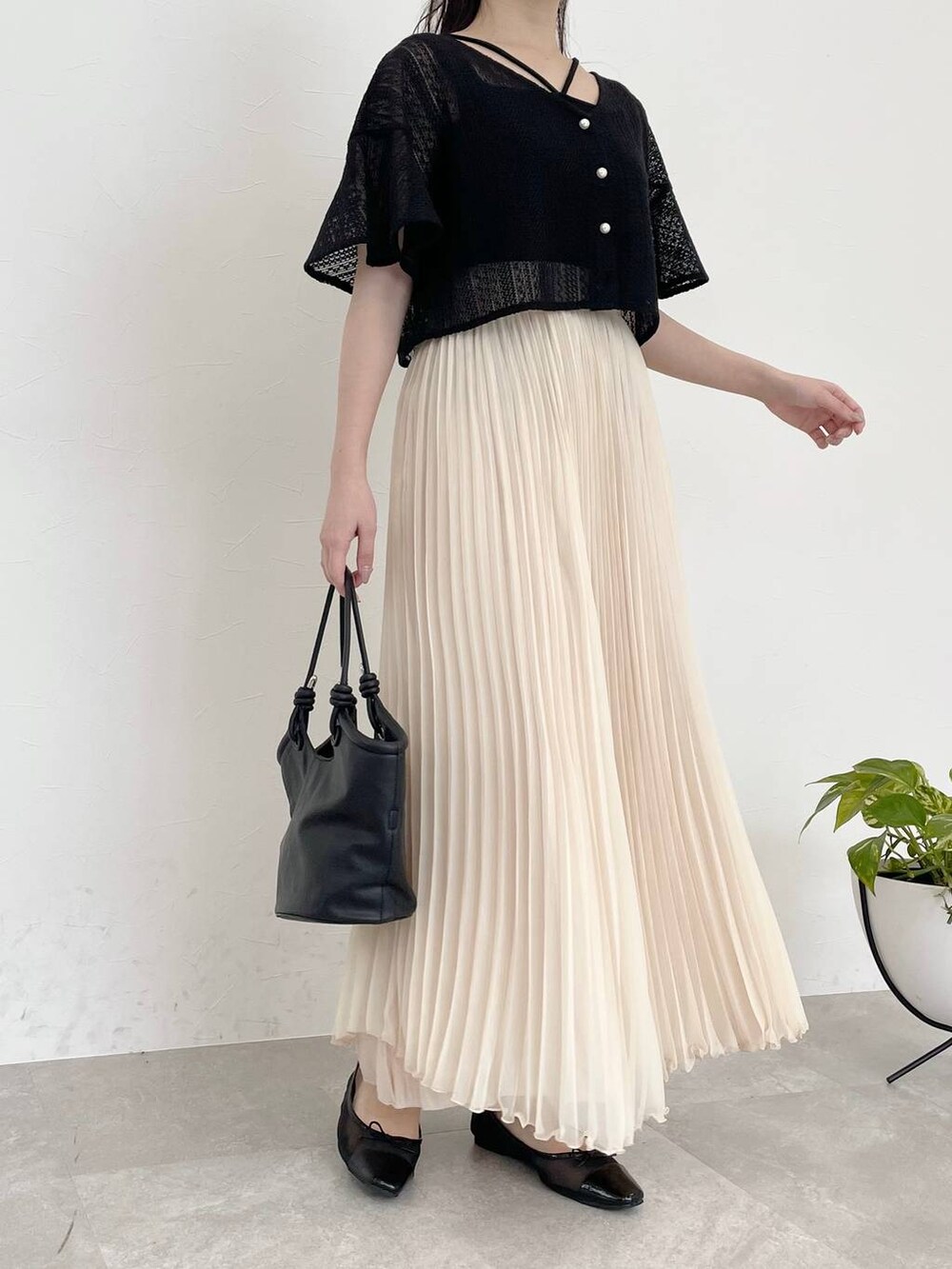 ブラック系のバレエシューズ、ブラック系のカーディガン/ボレロ、ホワイト系のスカートを着用したレディースの春コーディネートの4枚目の写真