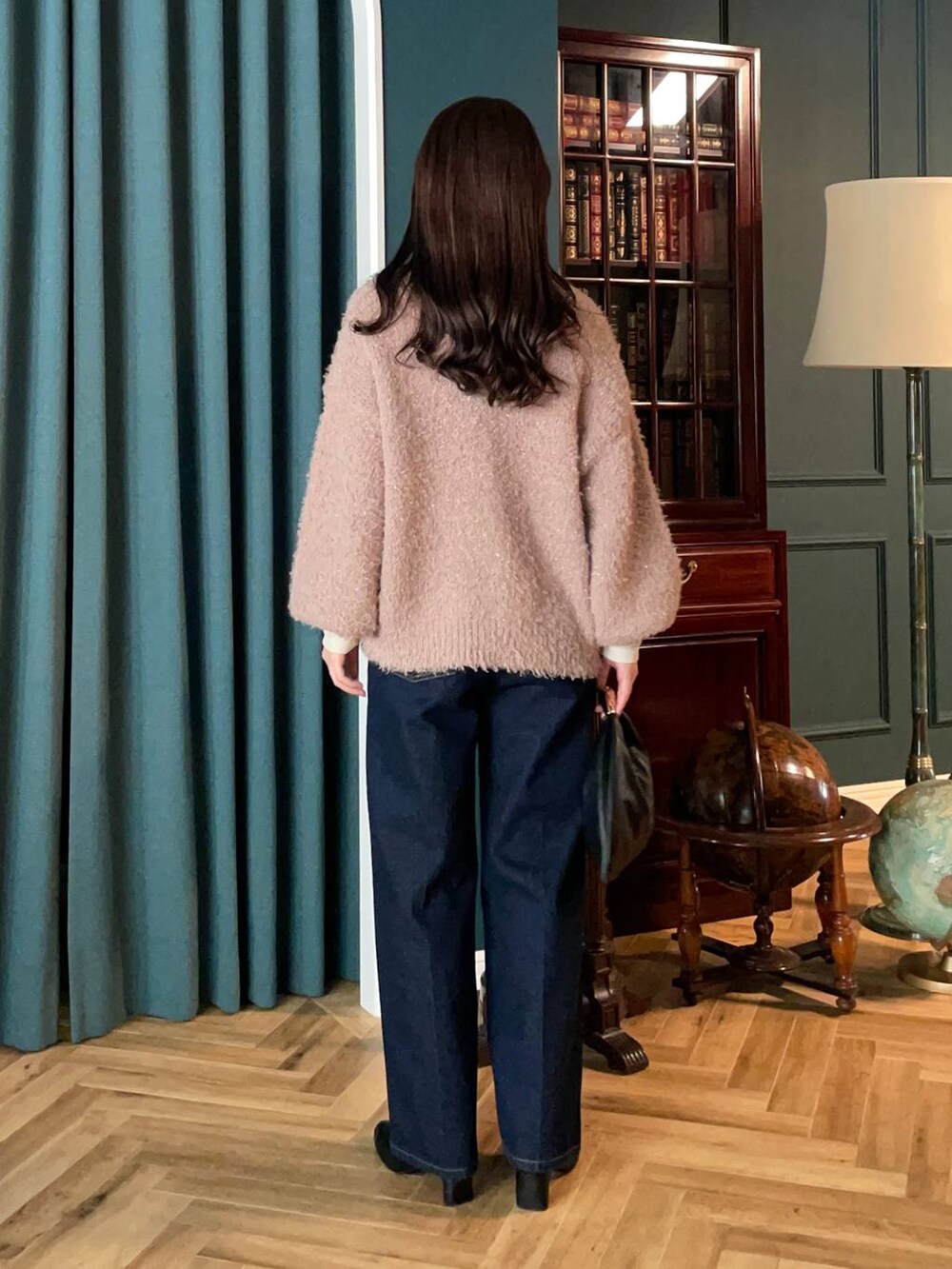 ブラック系のハンドバッグ、ベージュ系のカーディガン/ボレロ、ブルー系のデニムパンツを着用したレディースの秋コーディネートの2枚目の写真