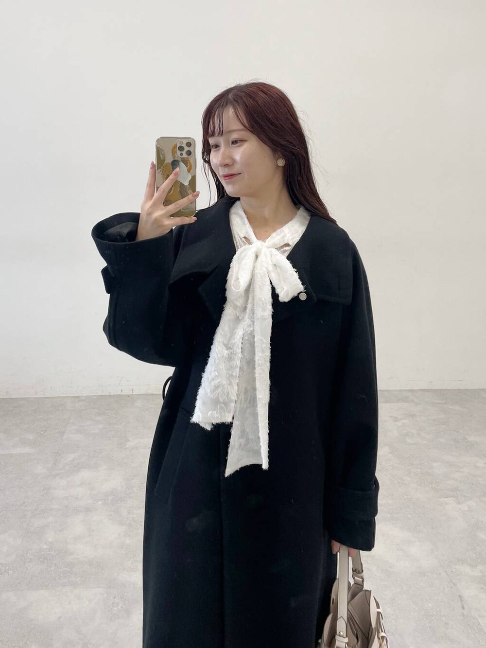 ブラック系のチェスターコート、ブラック系のワンピース、ホワイト系のショルダーバッグを着用したレディースの秋コーディネートの3枚目の写真