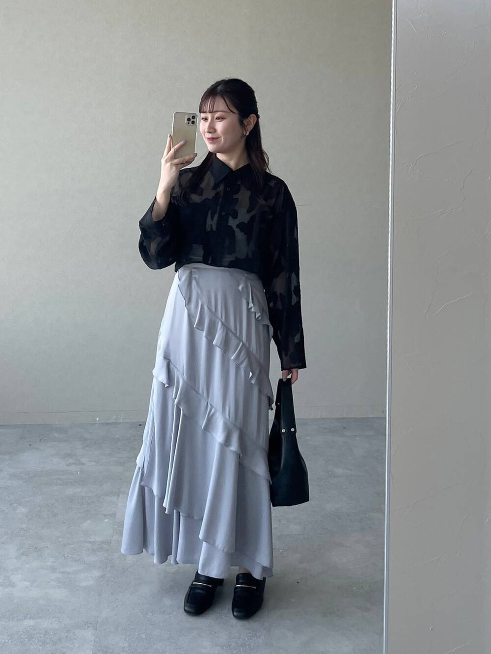 ブラック系のワンピース、ブラック系のショルダーバッグ、グレー系のスカートを着用したレディースの春コーディネートの3枚目の写真