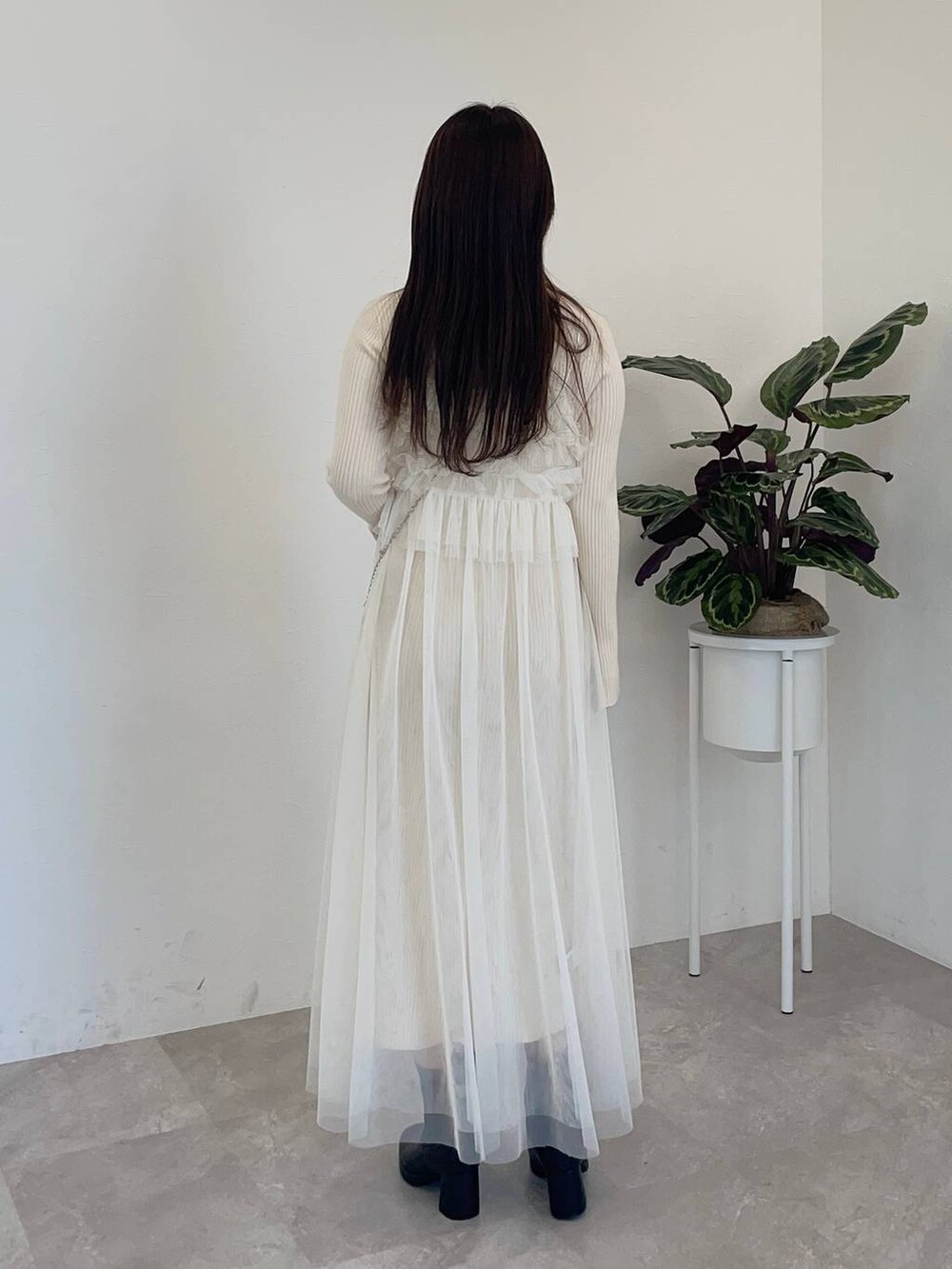 ブラック系のブーツ、ホワイト系のワンピース、ブラック系のショルダーバッグを着用したレディースの冬コーディネートの2枚目の写真