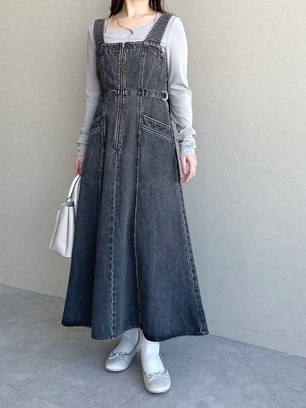 ブラック系のジャンパースカート、ベージュ系のショルダーバッグ、シルバー系のバレエシューズを着用したレディースの冬コーディネートの4枚目の写真