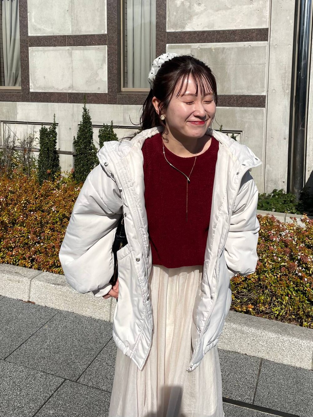 レッド系のニット/セーター、ホワイト系のブルゾン、ホワイト系のスカートを着用したレディースの秋コーディネートの4枚目の写真