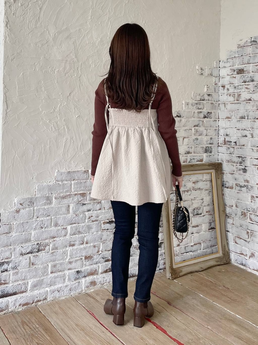 ブルー系のデニムパンツ、ベージュ系のキャミソール、ブラウン系のニット/セーターを着用したレディースの冬コーディネートの2枚目の写真