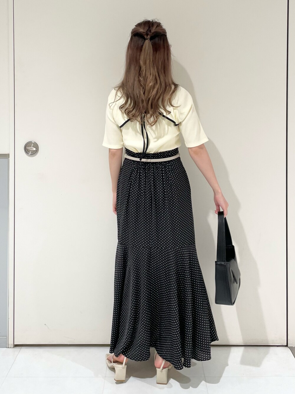 ホワイト系のTシャツ/カットソー、ブラック系のスカート、ブラック系のハンドバッグを着用したレディースの夏コーディネートの2枚目の写真