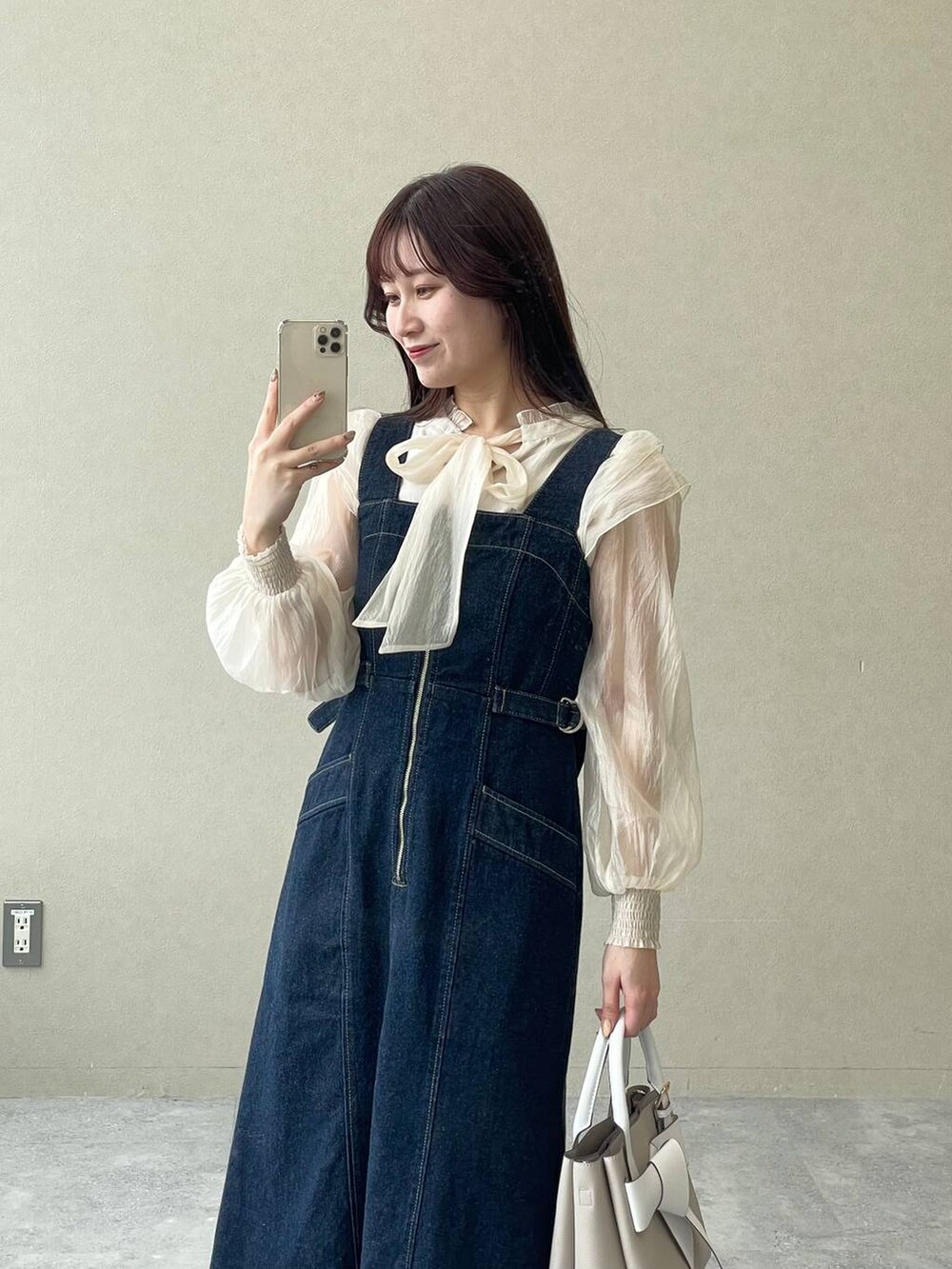 ブルー系のジャンパースカート、ベージュ系のショルダーバッグ、ブラウン系のパンプスを着用したレディースの冬コーディネートの3枚目の写真