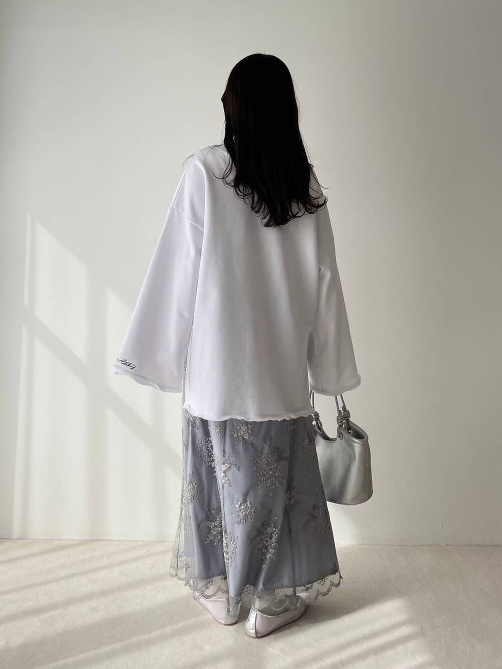 シルバー系のバレエシューズ、ホワイト系のスウェット、ブルー系のスカートを着用したレディースの春コーディネートの3枚目の写真