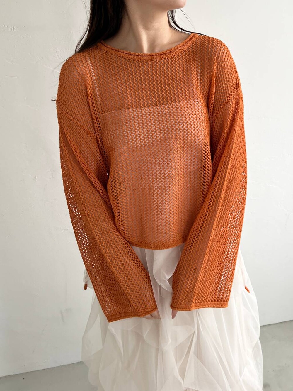 ホワイト系のスカート、オレンジ系のニット/セーター、ベージュ系のショルダーバッグを着用したレディースの夏コーディネートの3枚目の写真