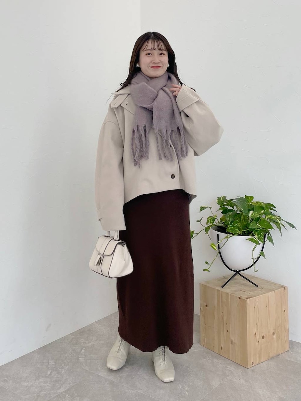 ホワイト系のその他アウター、ホワイト系のハンドバッグ、ホワイト系のブーツを着用したレディースの冬コーディネートの2枚目の写真