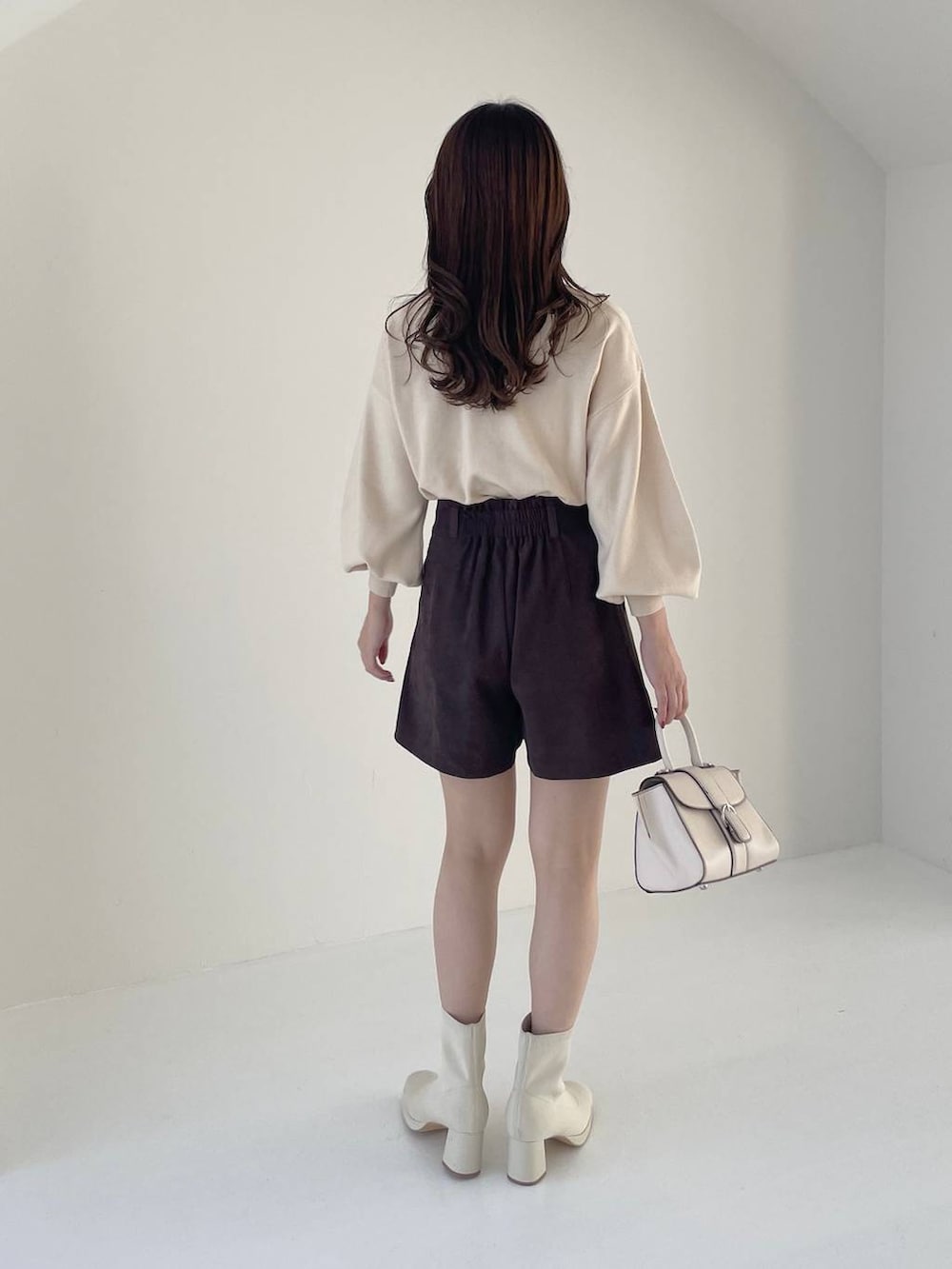 ホワイト系のハンドバッグ、ホワイト系のブーツ、ホワイト系のニット/セーターを着用したレディースの秋コーディネートの5枚目の写真