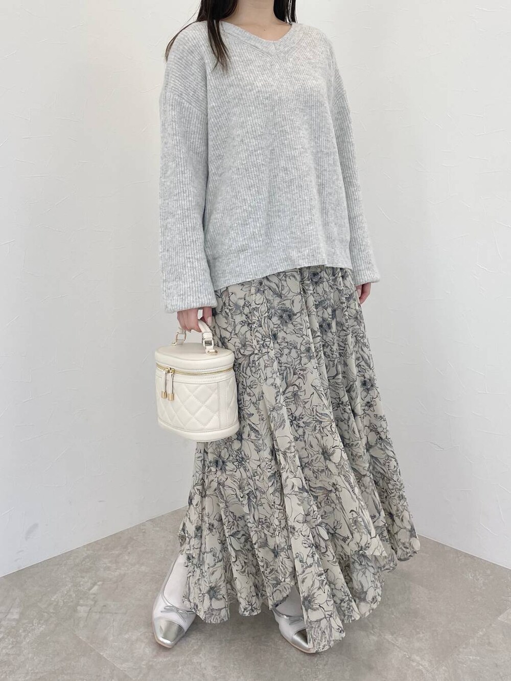 グレー系のニット/セーター、ベージュ系のスカート、ホワイト系のショルダーバッグを着用したレディースの冬コーディネートの7枚目の写真