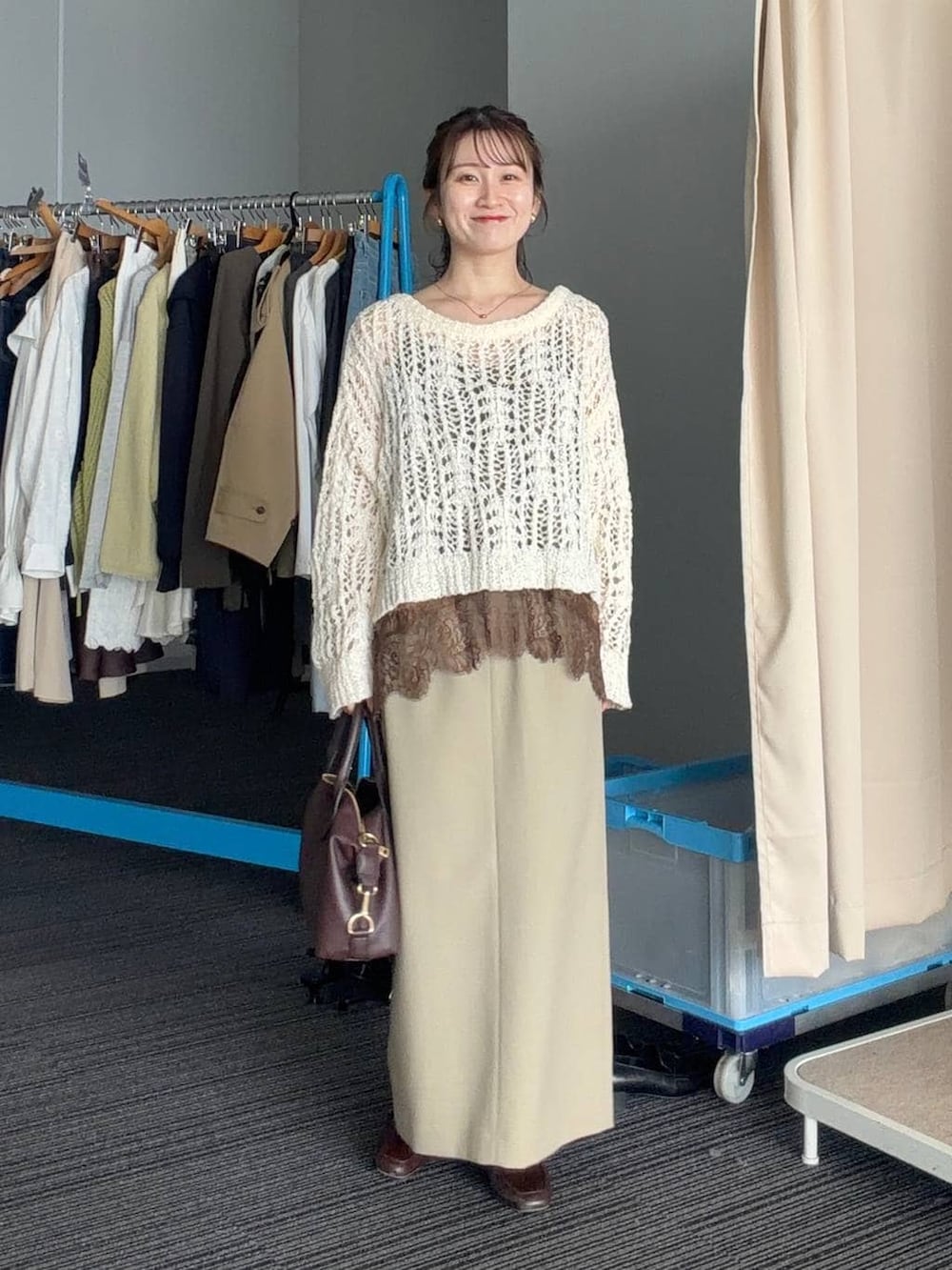 ブラウン系のボストンバッグ、ベージュ系のスカート、ブラウン系のブルゾンを着用したレディースの春コーディネートの3枚目の写真