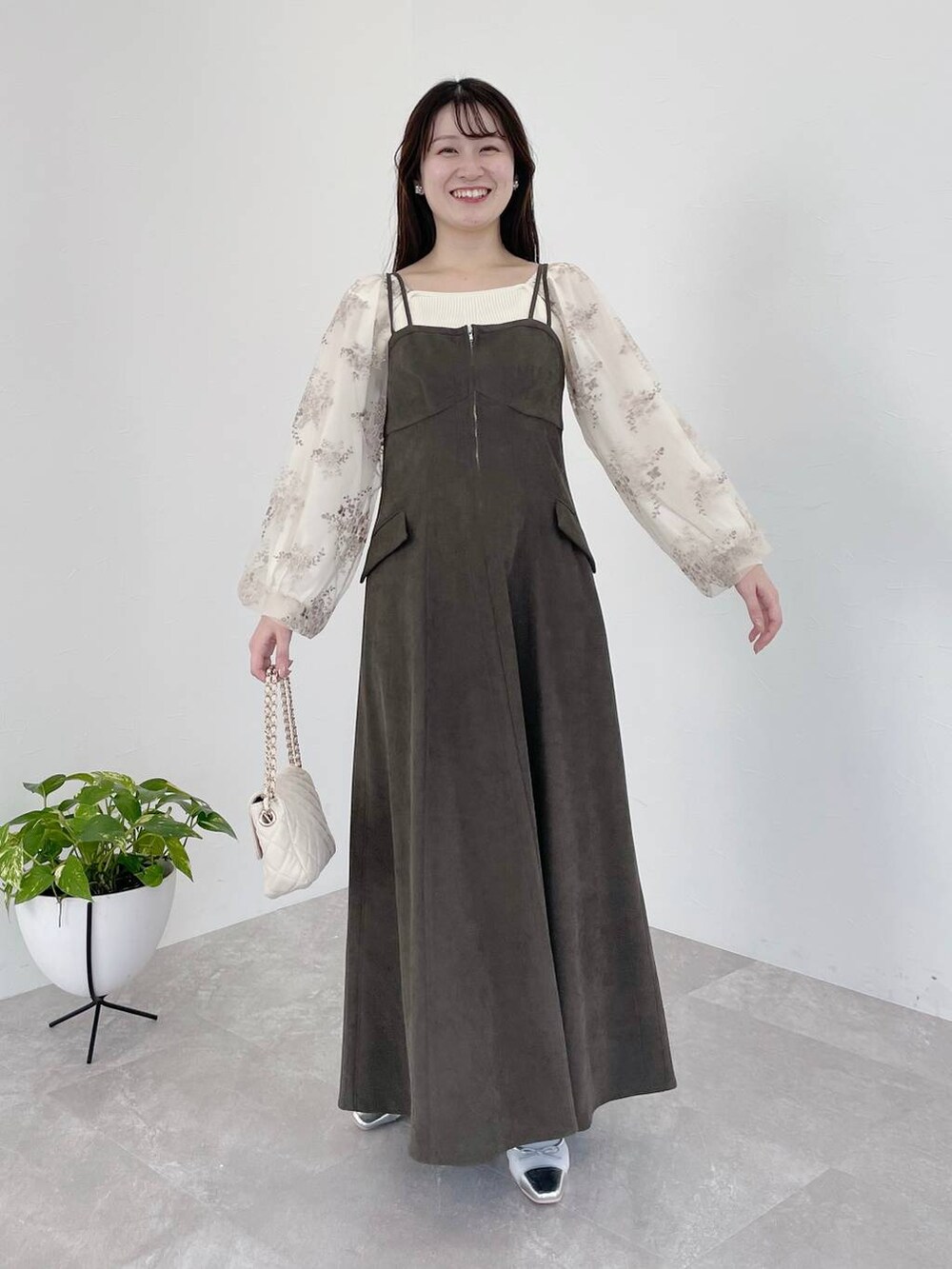 グレー系のワンピース、ホワイト系のショルダーバッグ、ホワイト系のニット/セーターを着用したレディースの冬コーディネートの2枚目の写真