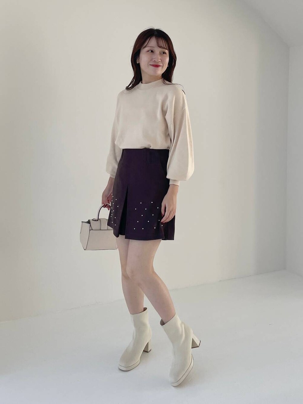 ホワイト系のハンドバッグ、ホワイト系のブーツ、ホワイト系のニット/セーターを着用したレディースの秋コーディネートの4枚目の写真