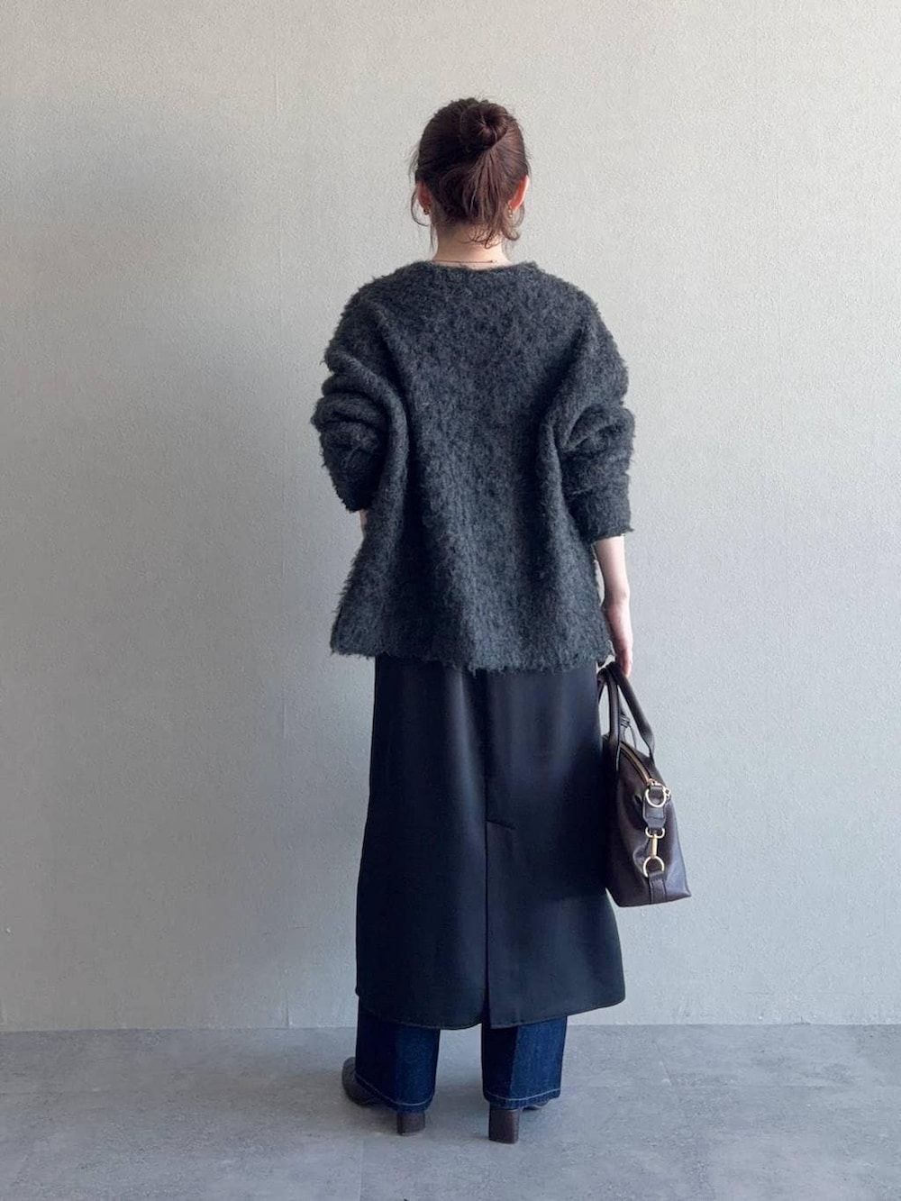 ブラウン系のボストンバッグ、ブルー系のデニムパンツ、ブラウン系のブーツを着用したレディースの冬コーディネートの2枚目の写真