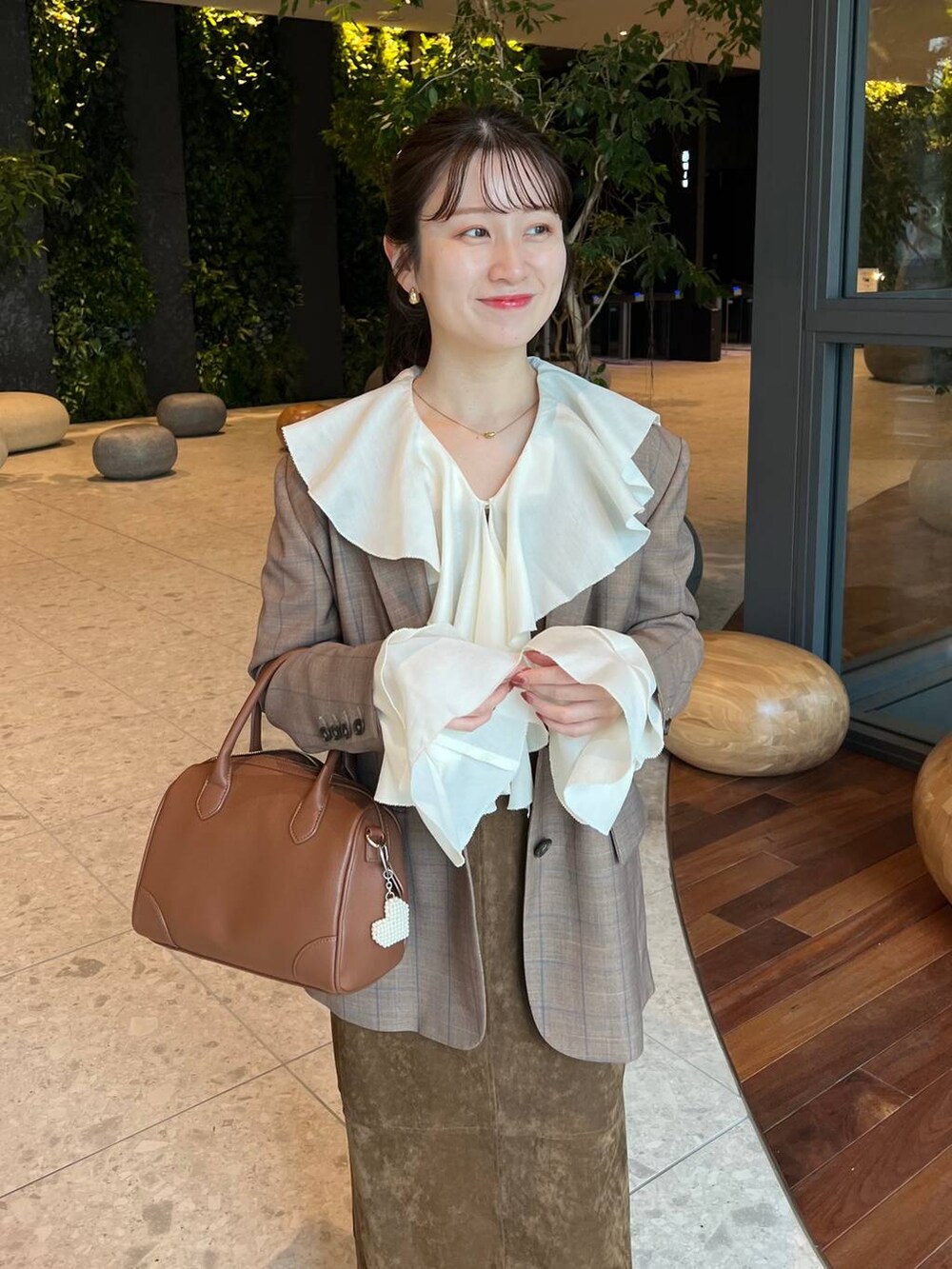 ブラウン系のショルダーバッグ、ホワイト系のシャツ/ブラウス、ベージュ系のテーラードジャケットを着用したレディースの秋コーディネートの3枚目の写真