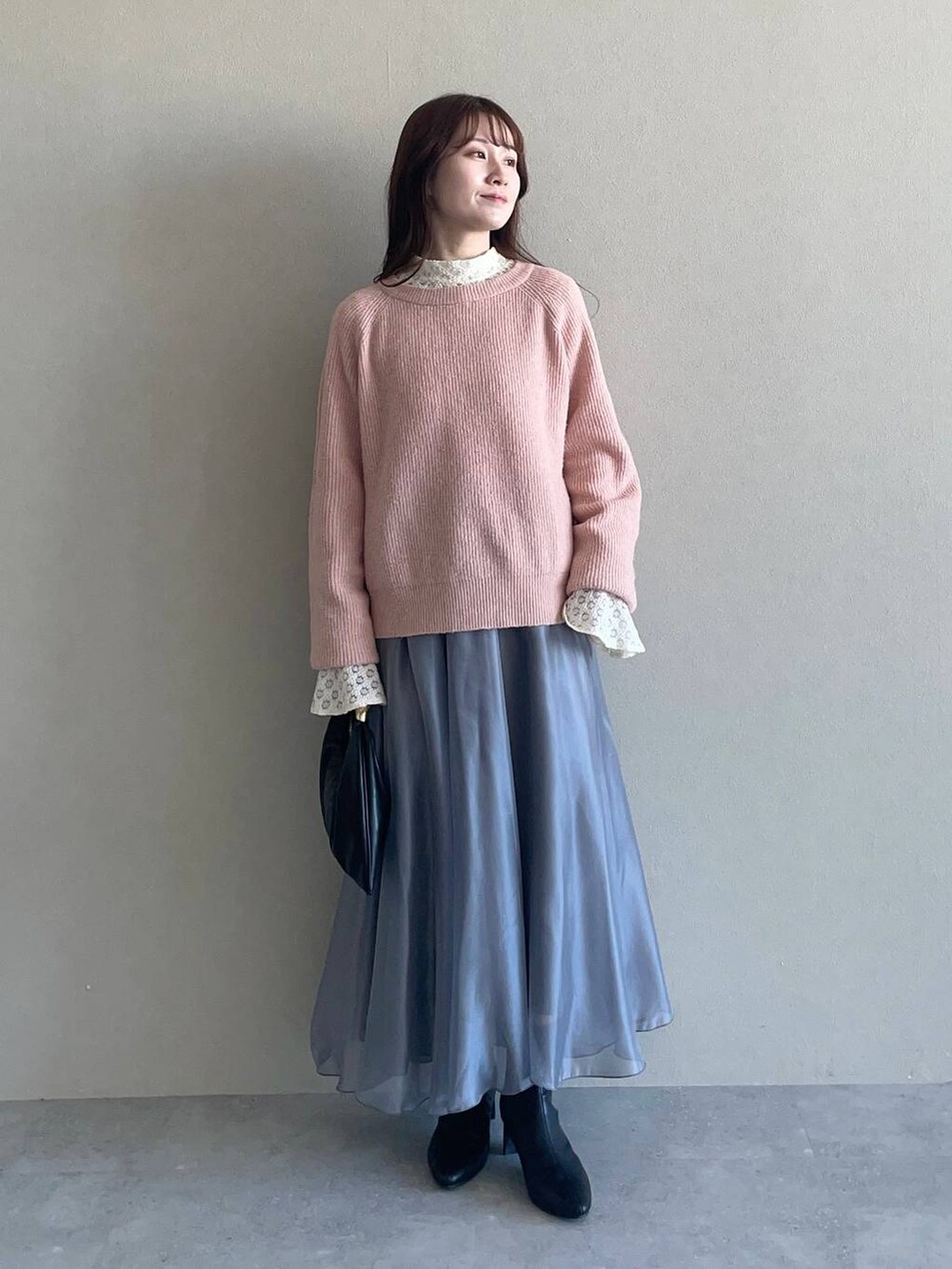 ピンク系のニット/セーター、ブラック系のハンドバッグ、ブラック系のブーツを着用したレディースの冬コーディネートの3枚目の写真