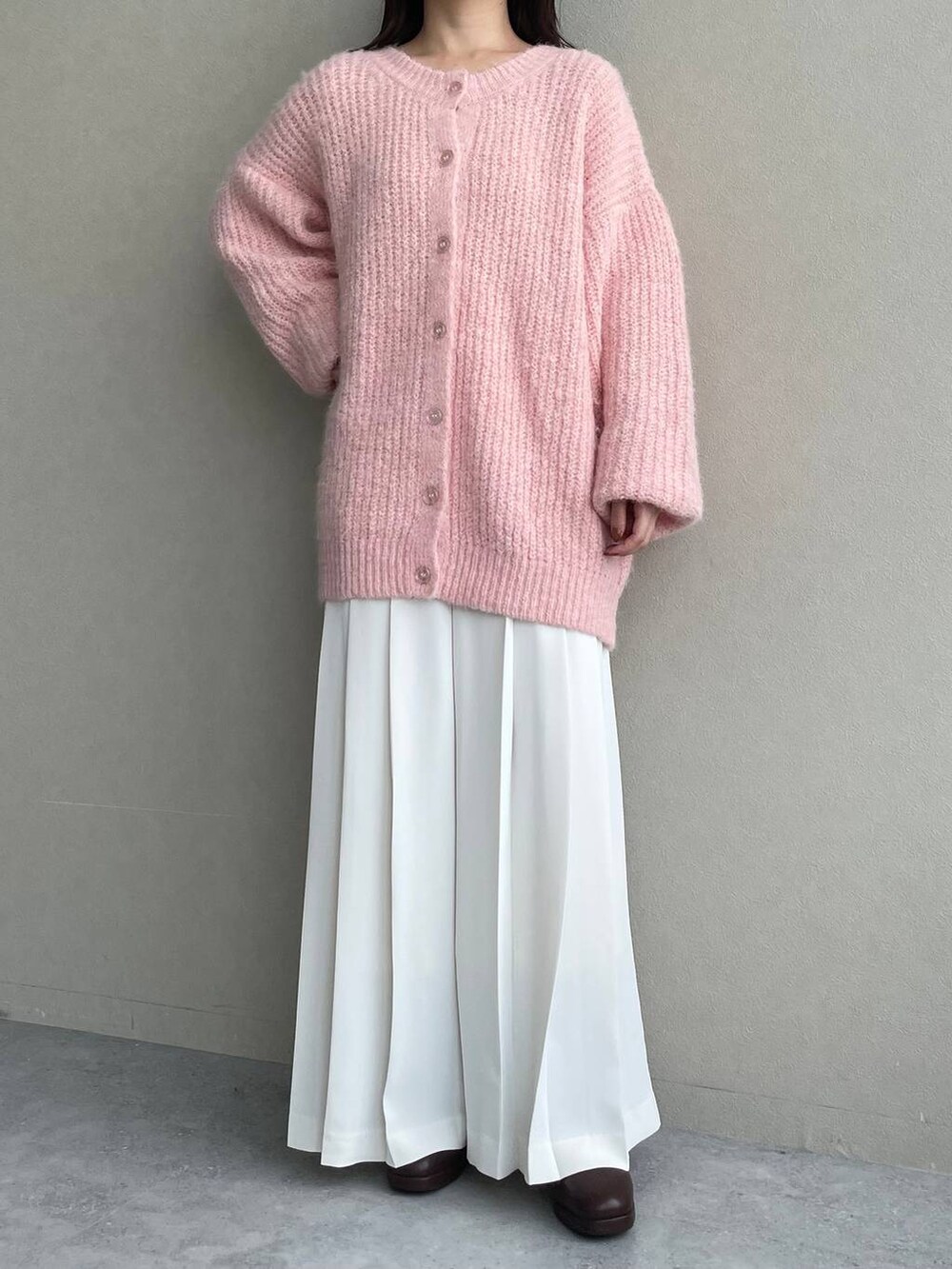 ブラウン系のブーツ、ピンク系のカーディガン/ボレロ、ブラウン系のハンドバッグを着用したレディースの秋コーディネートの7枚目の写真