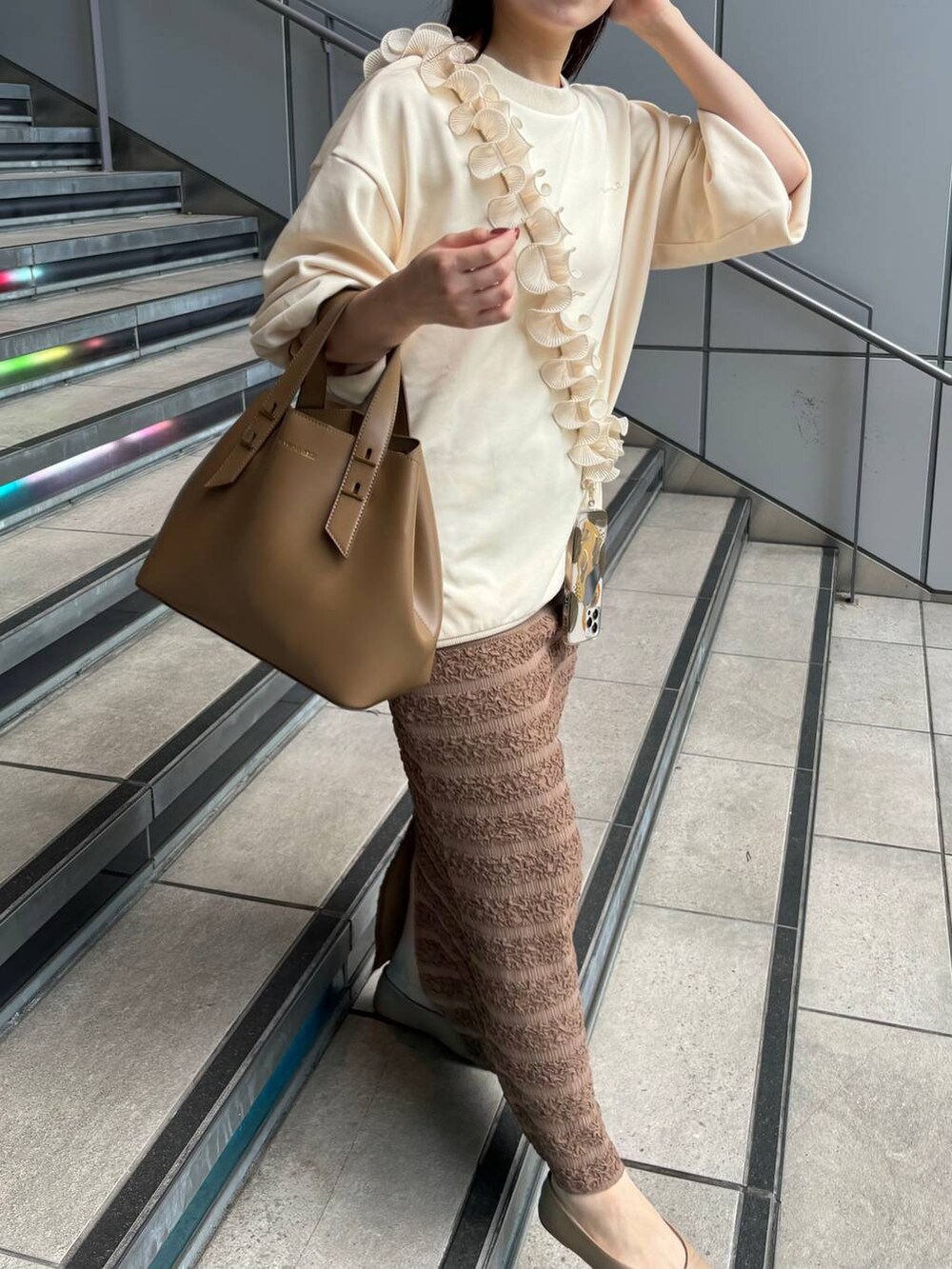 ホワイト系のスウェット、ブラウン系のスカート、ホワイト系のスマホグッズを着用したレディースの秋コーディネートの3枚目の写真