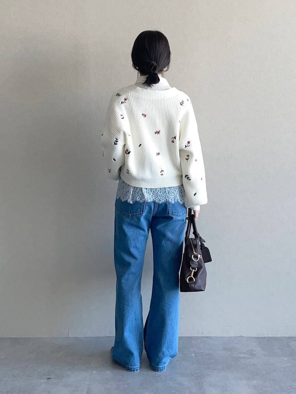 ブラウン系のボストンバッグ、ブラック系のローファー、ブルー系のデニムパンツを着用したレディースの冬コーディネートの2枚目の写真