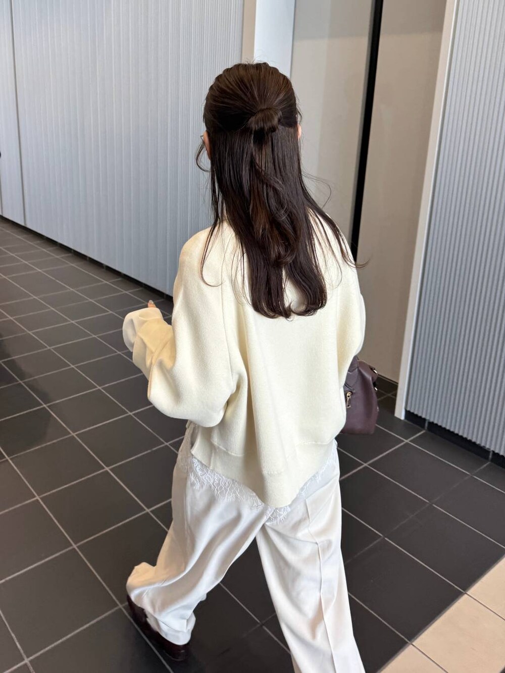 ブラウン系のボストンバッグ、ホワイト系のスラックス、ホワイト系のニット/セーターを着用したレディースの冬コーディネートの4枚目の写真