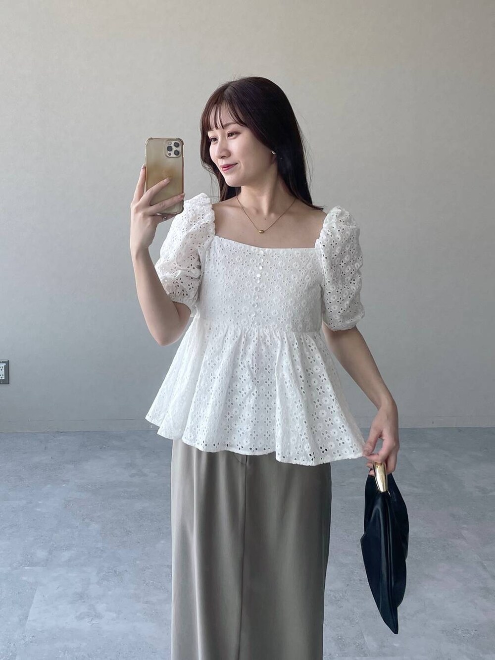 ブラック系のハンドバッグ、ベージュ系のスカート、ホワイト系のシャツ/ブラウスを着用したレディースの夏コーディネートの3枚目の写真