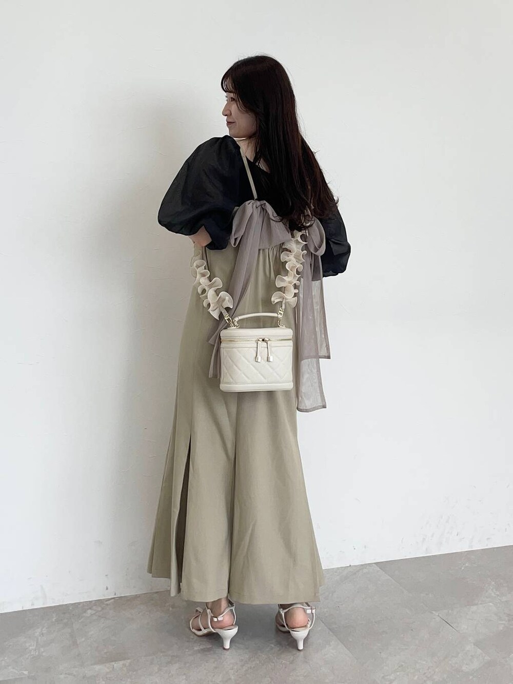 ベージュ系のワンピース、ブラック系のTシャツ/カットソー、ホワイト系のサンダルを着用したレディースの夏コーディネートの2枚目の写真