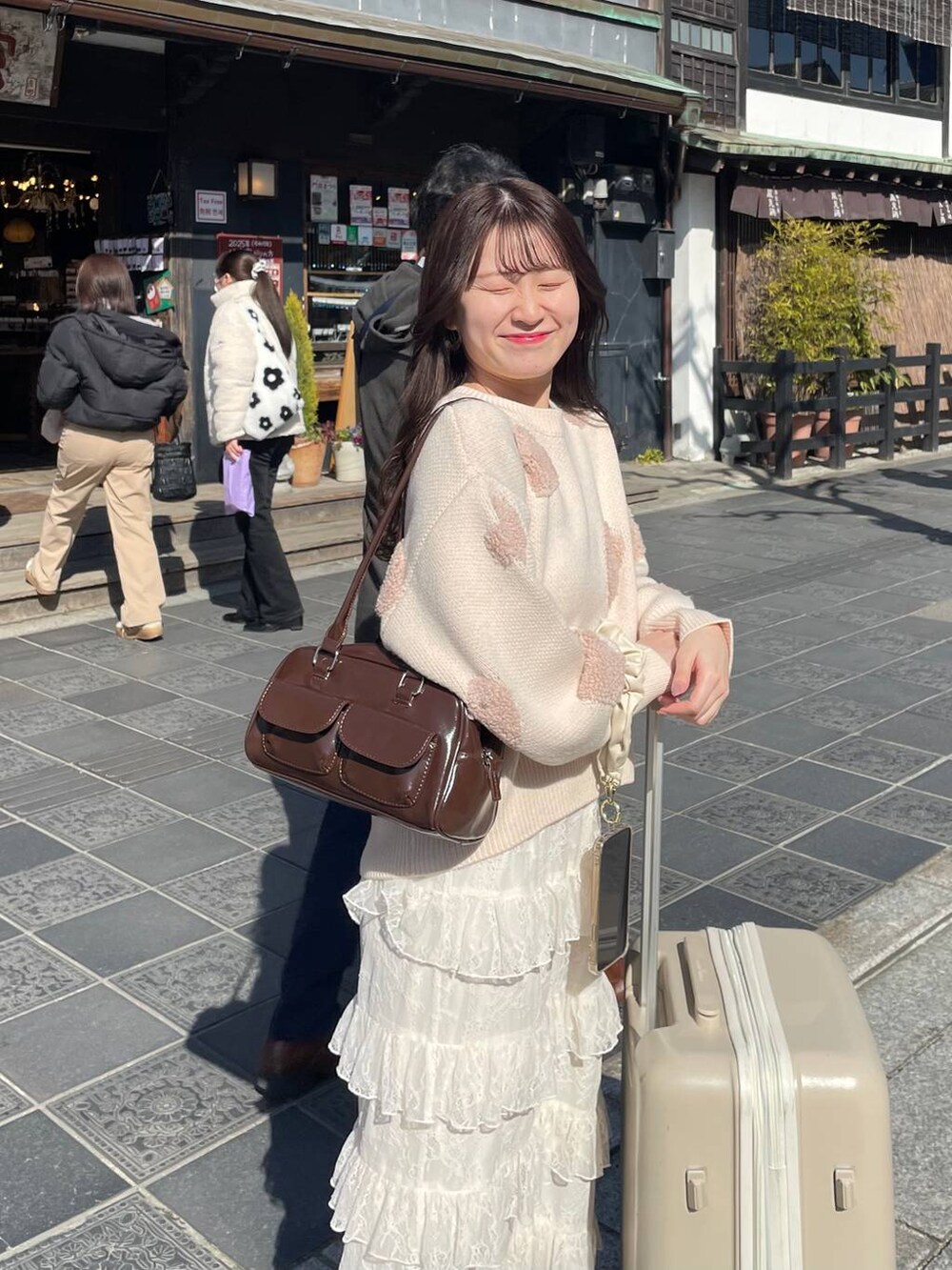 ブラウン系のハンドバッグ、ホワイト系のニット/セーター、ホワイト系のスカートを着用したレディースの冬コーディネートの3枚目の写真