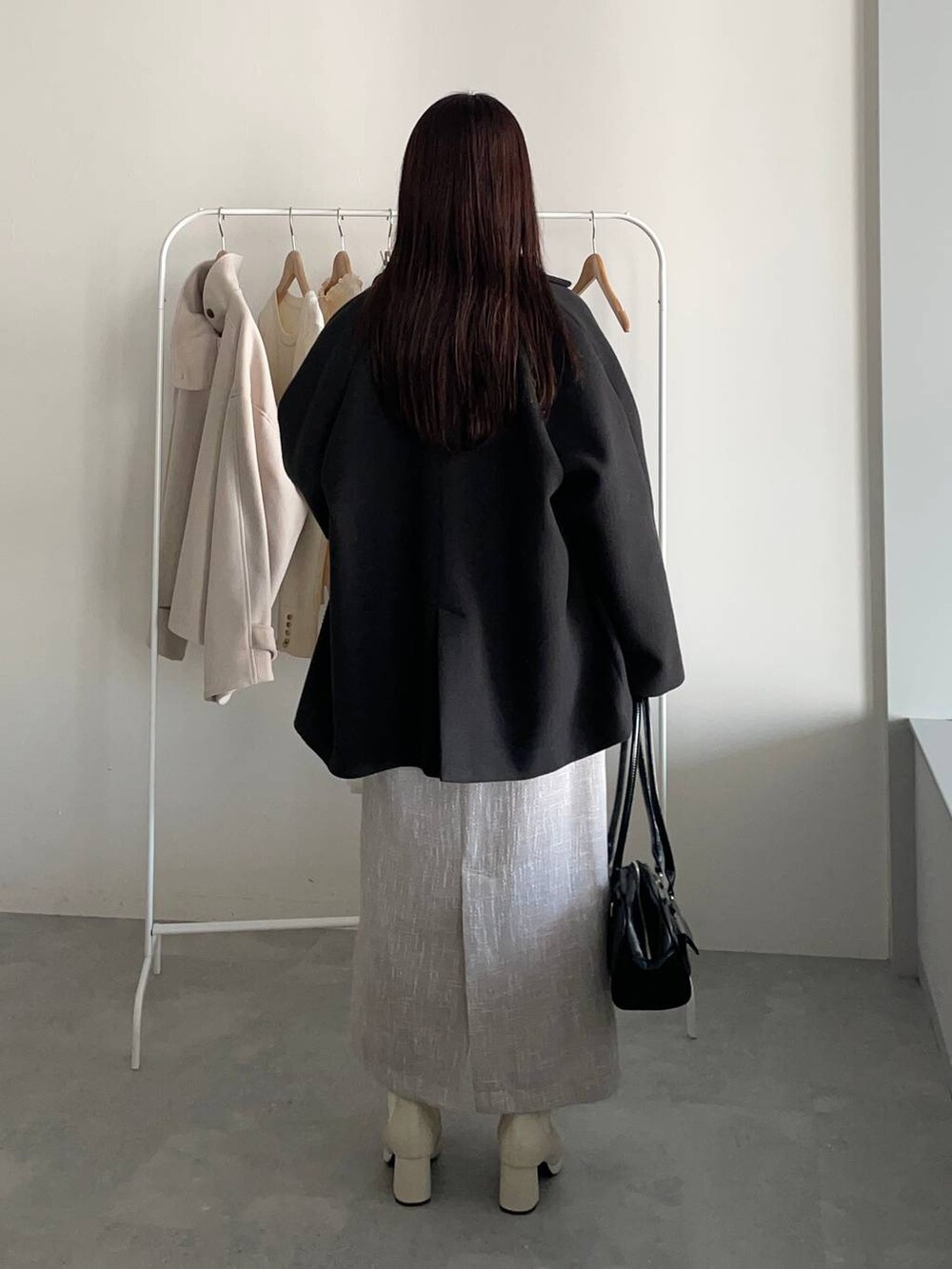 ブラック系のその他アウター、ホワイト系のブーツ、ブラック系のハンドバッグを着用したレディースの冬コーディネートの2枚目の写真