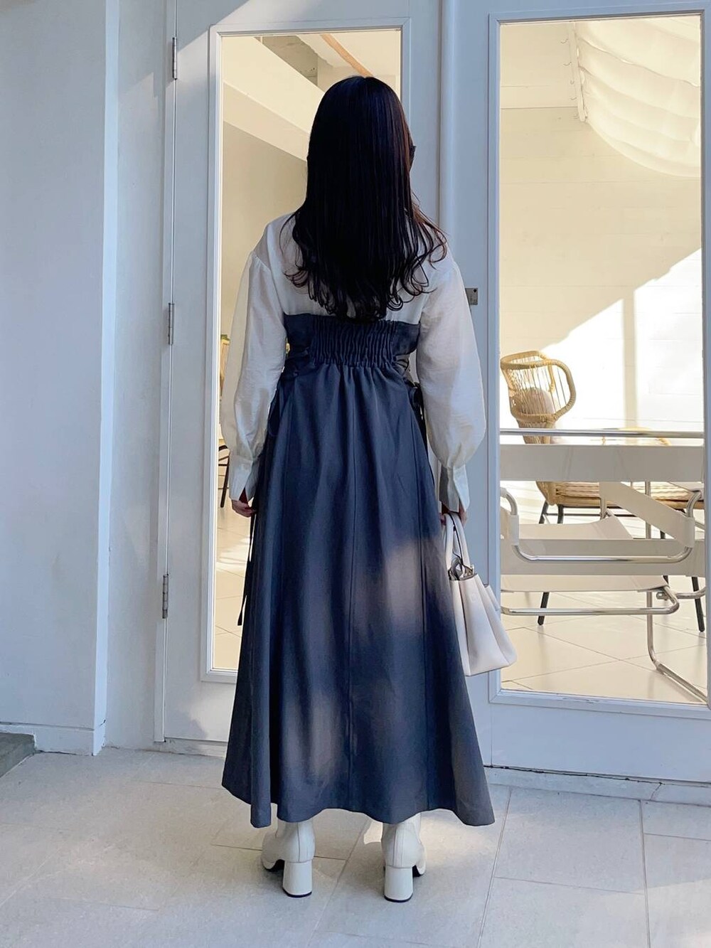 ホワイト系のブーツ、ホワイト系のショルダーバッグ、グレー系のワンピースを着用したレディースの冬コーディネートの2枚目の写真