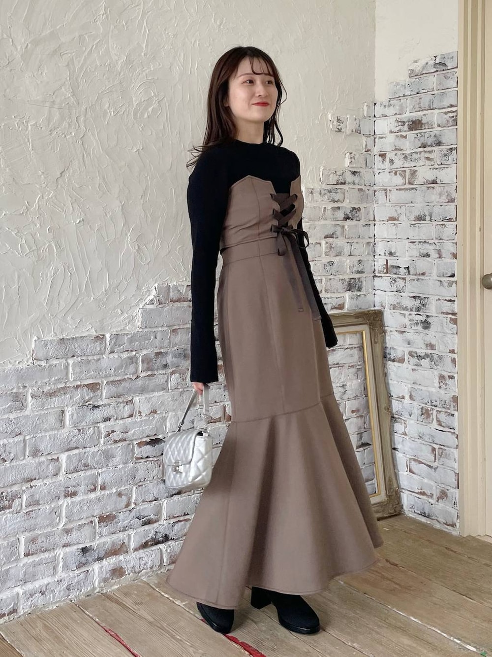 ブラック系のブーツ、ブラウン系のスカート、ブラック系のニット/セーターを着用したレディースの秋コーディネートの2枚目の写真