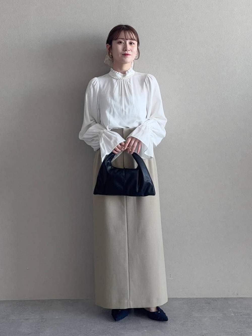 ブラック系のハンドバッグ、ベージュ系のテーラードジャケット、ベージュ系のスカートを着用したレディースの冬コーディネートの3枚目の写真