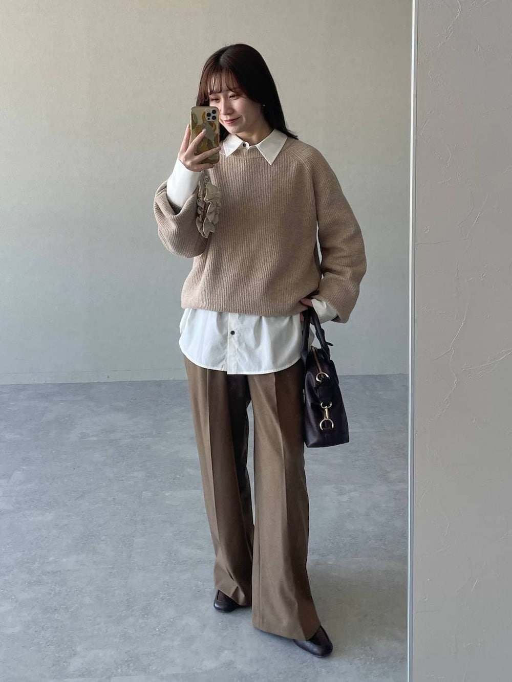 ベージュ系のピーコート、ベージュ系のニット/セーター、ブラウン系のボストンバッグを着用したレディースの冬コーディネートの3枚目の写真