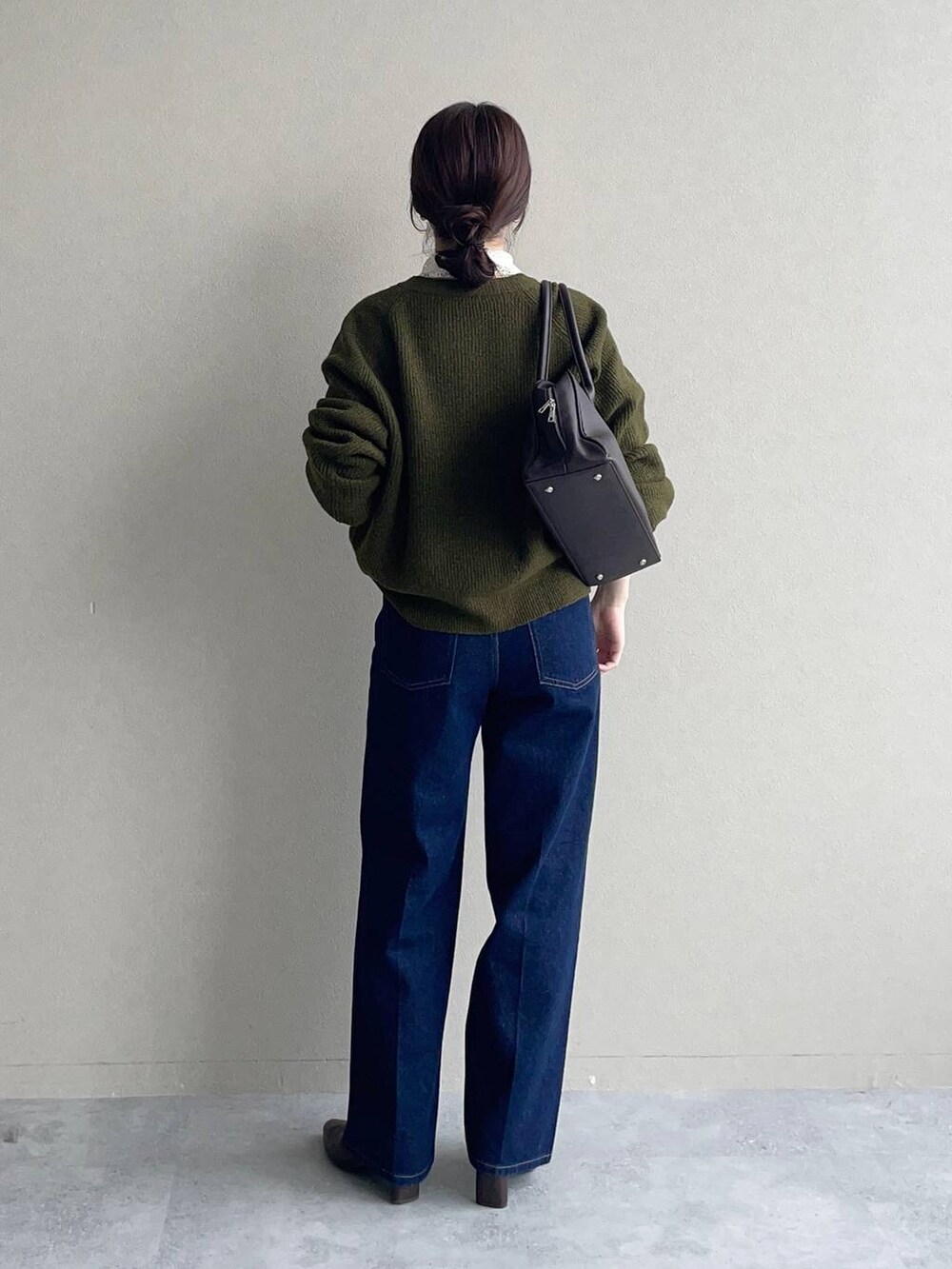 グリーン系のニット/セーター、ホワイト系のシャツ/ブラウス、ブルー系のデニムパンツを着用したレディースの秋コーディネートの3枚目の写真