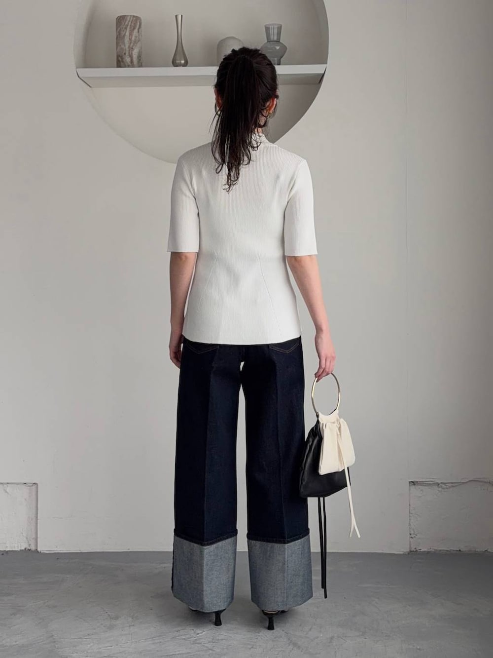 ホワイト系のサンダル、ブルー系のデニムパンツ、ブラック系のハンドバッグを着用したレディースの春コーディネートの2枚目の写真