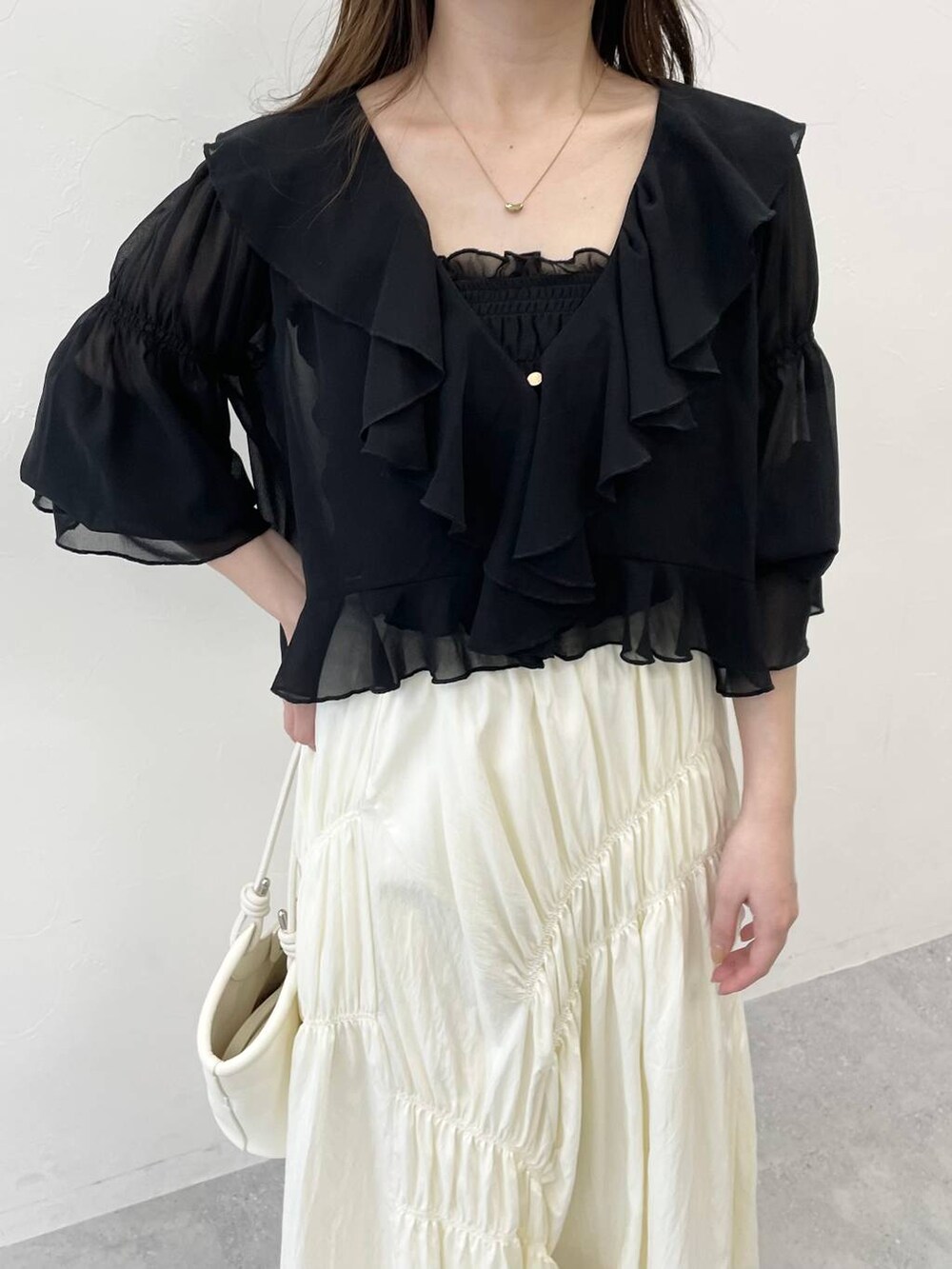 ブラック系のシャツ/ブラウス、ブラック系のハンドバッグ、ホワイト系のサンダルを着用したレディースの春コーディネートの3枚目の写真